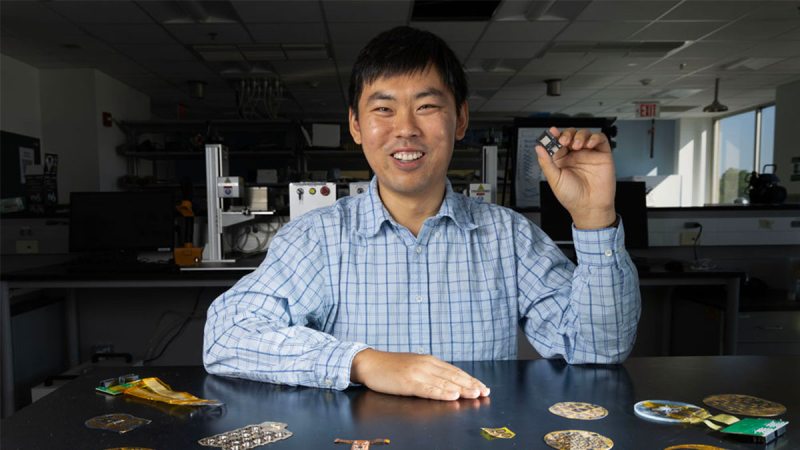 Wubin Bai in a lab holding a device he created.