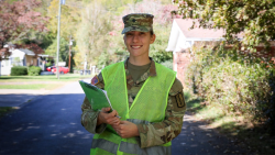 Jessica Bowling posing for a portrait in her National Guard uniform while holding a clipboard while walking around a neighborhood in Waynesville, N.C.