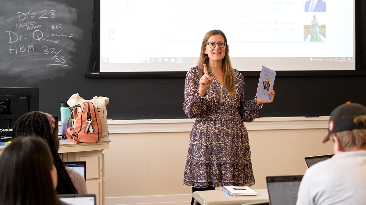 Heather Knorr leading a Spanish class at UNC-Chapel Hill. She's holding a book past students wrote in a prior year's class.