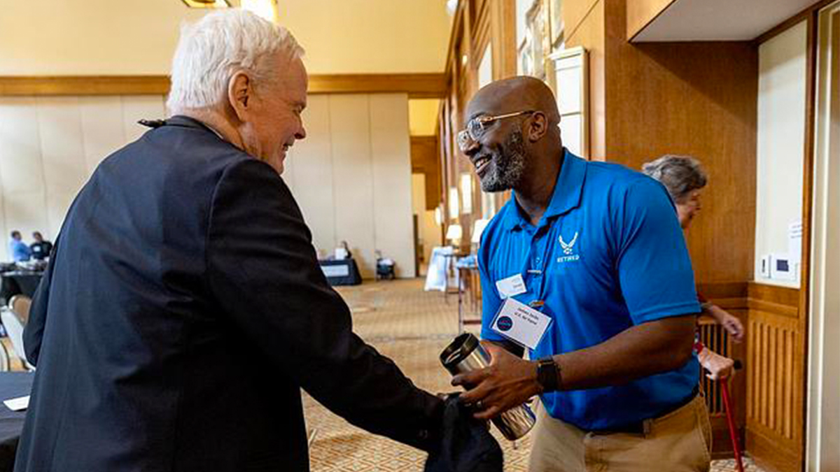 James Jacks shaking hands with an individual.