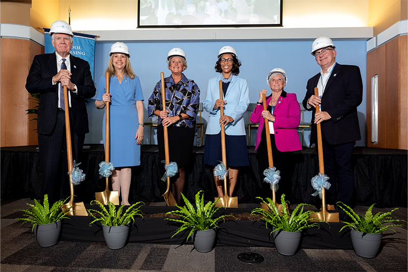 Bill Conway, Amy Galey, Dean Valerie Howard, Brandi Newman, Gale Adcock and CHris Clemens putting shovels in dirt at a nursing building groundbreaking event.