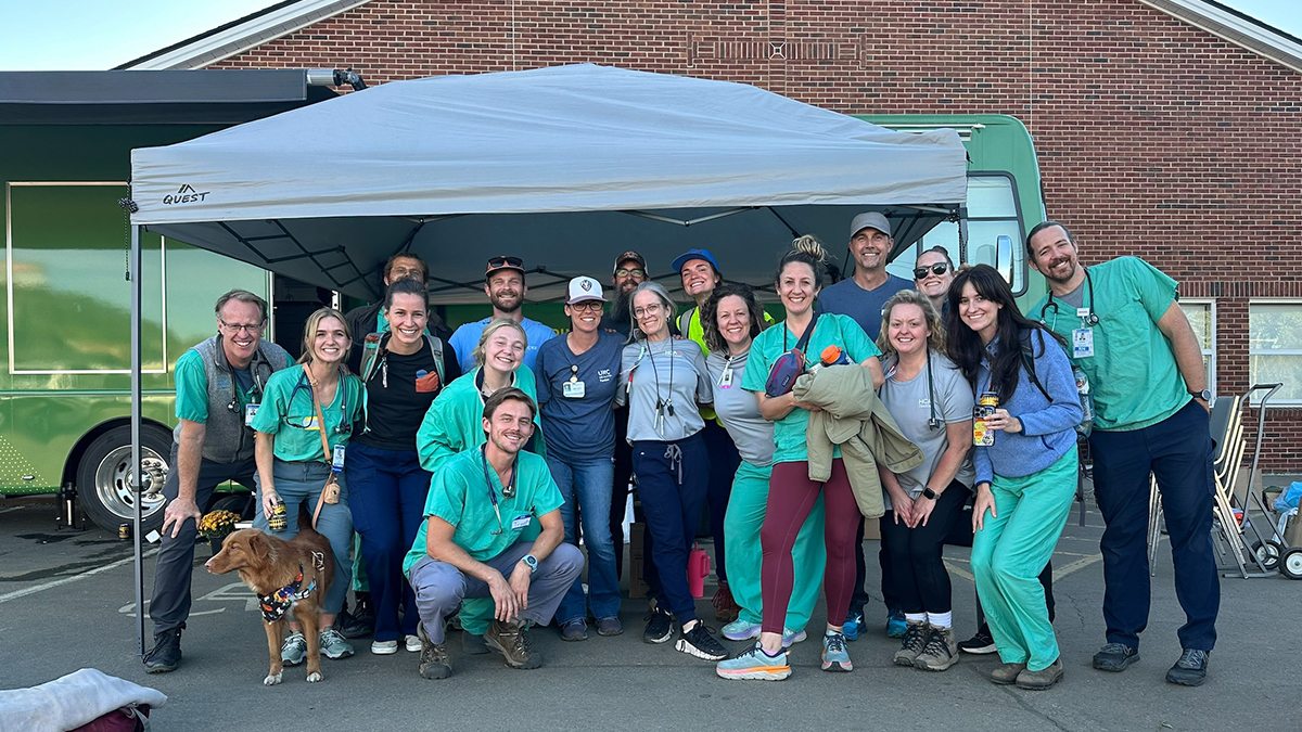 Individuals posing under tent set up for hurricane relief.